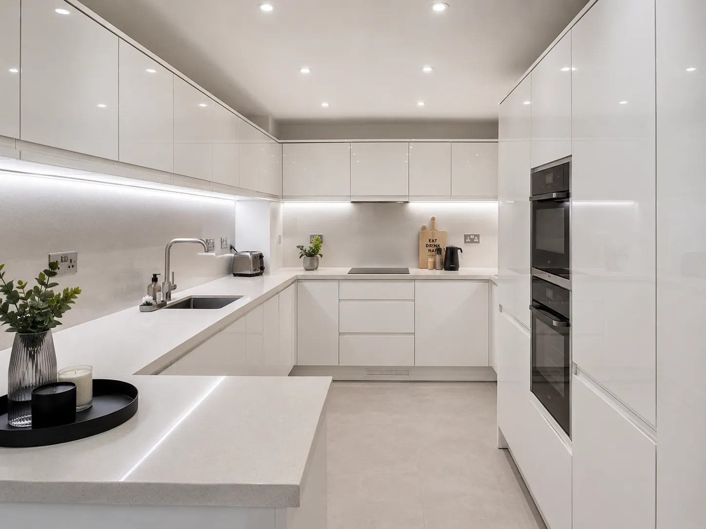 A beautiful modern space demonstrating perfect kitchen lighting without windows using reflective surfaces and bright LEDs.