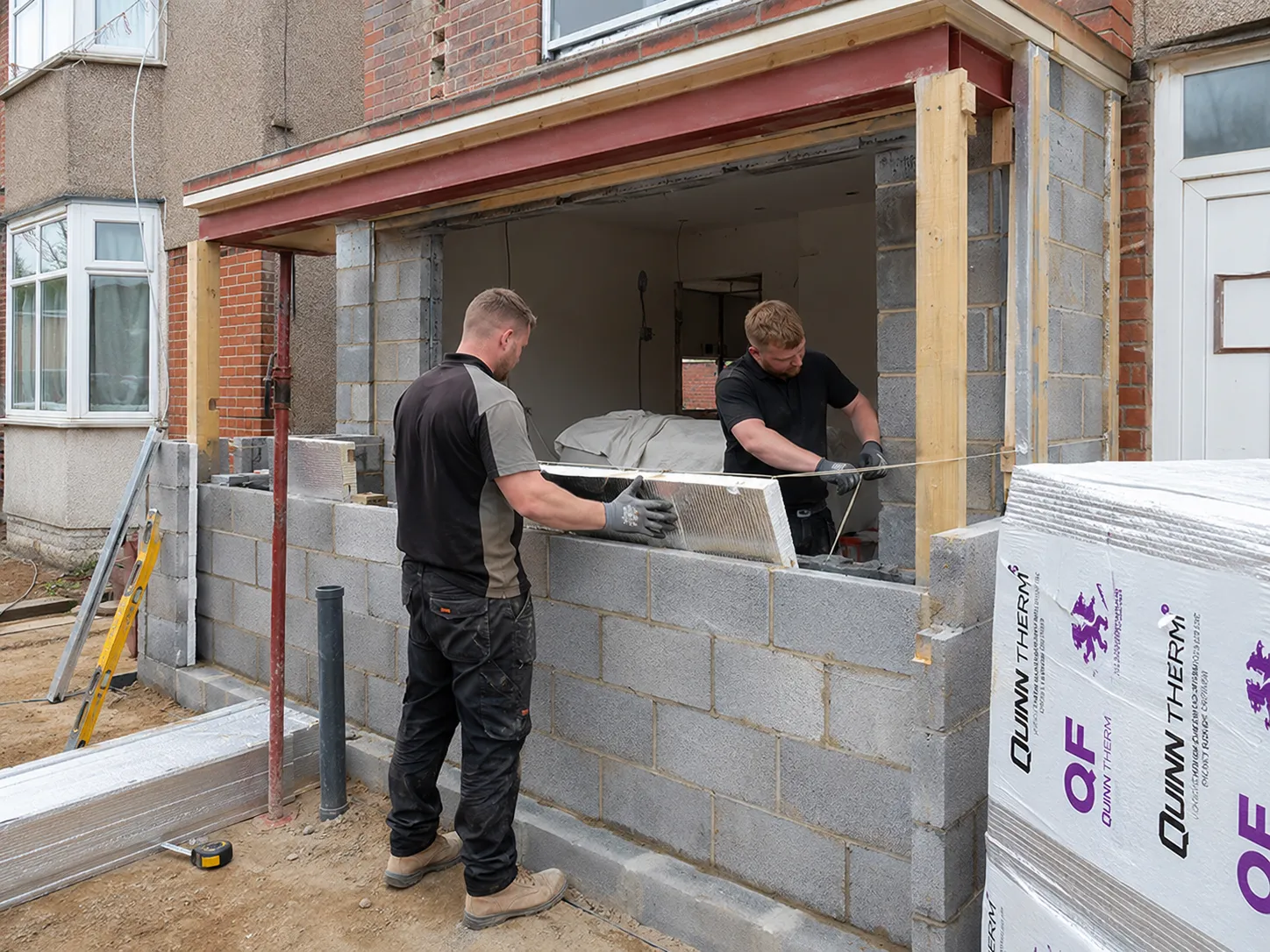 Builders installing rigid PIR insulation panels into the cavity wall of a new extension.